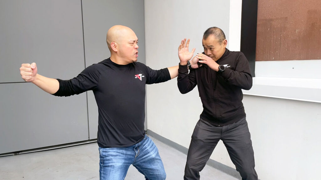 The first order of business is to protect yourself from the immediate threat. Dr. Conrad Bui (right) of Tiga Tactics demonstrates how he would defend himself against a wild punch common among untrained attackers.