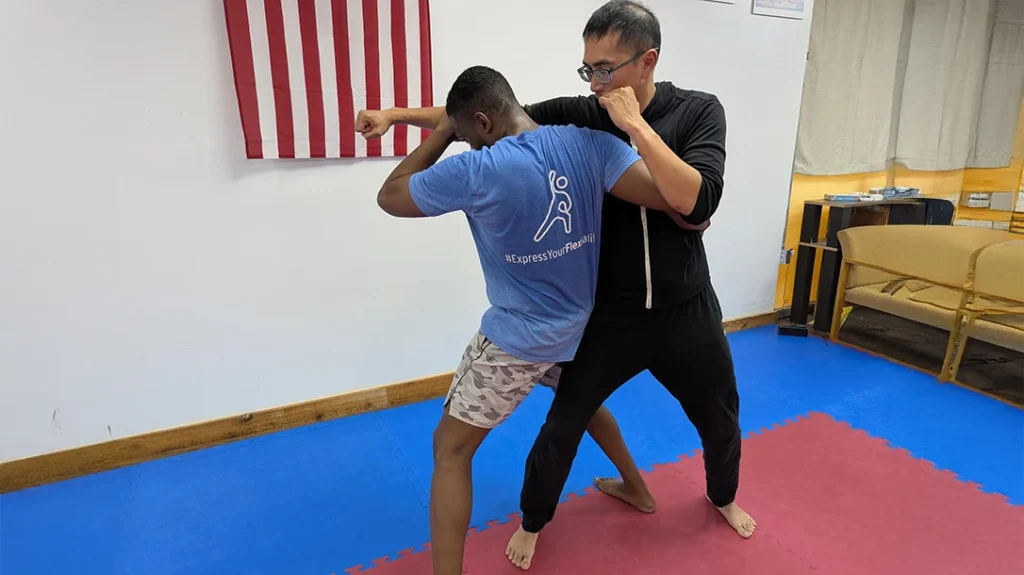 Brian steps in behind Adam’s lead leg and wraps his opposite arm around Adam’s waist/ribs and under Adam’s shoulder.