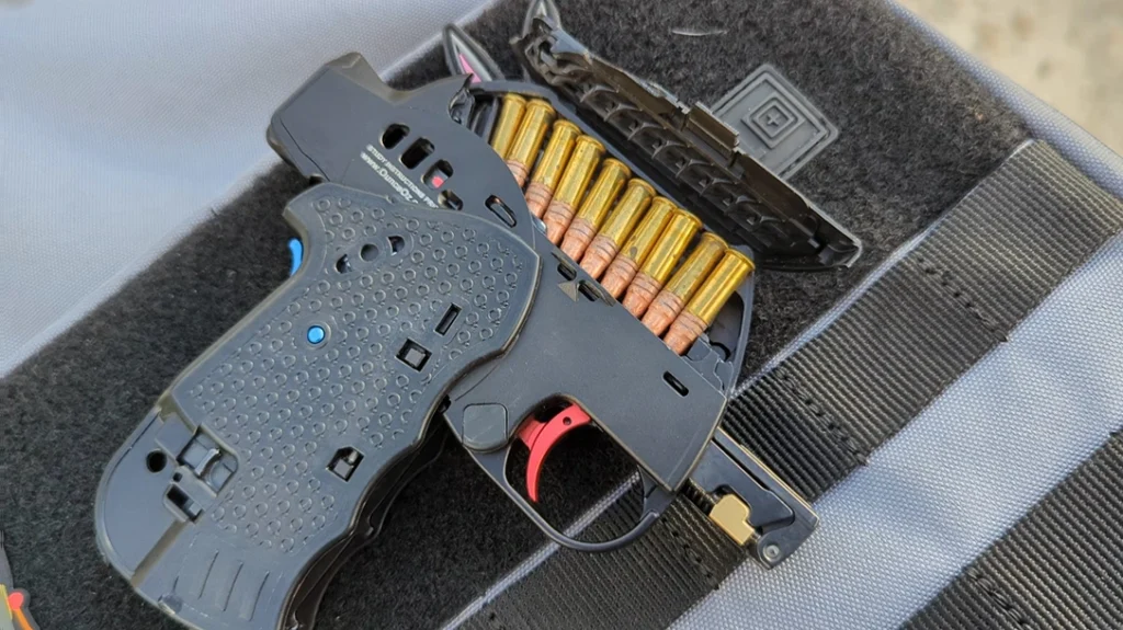 It features a top-mounted magazine. It’s an integral magazine that is loaded by opening a small door and just dropping the rounds into the gun.