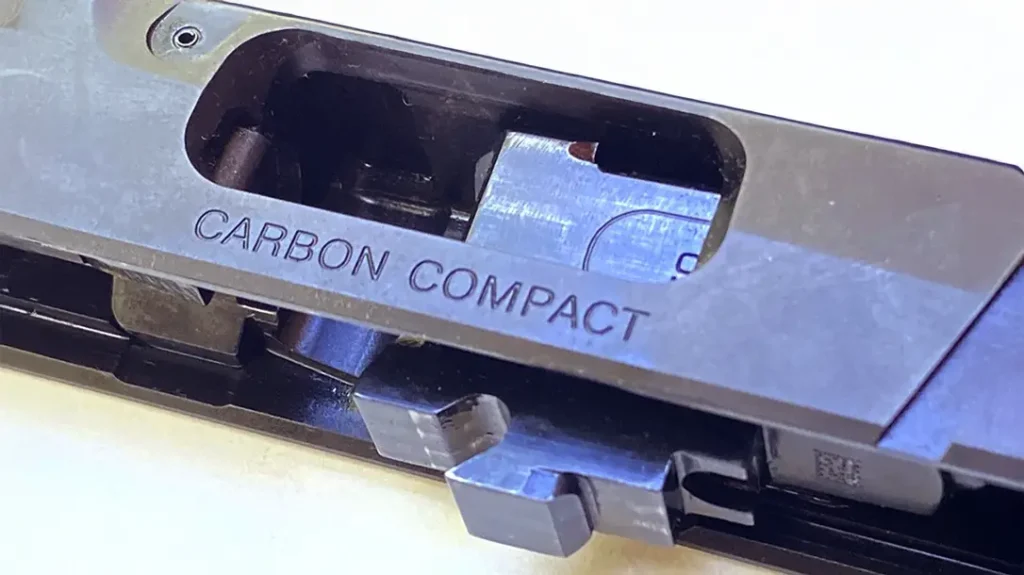 A rectangular locking lug protrudes from the top rear of the barrel chamber and mates with a matching cavity machined into the top of the slide.